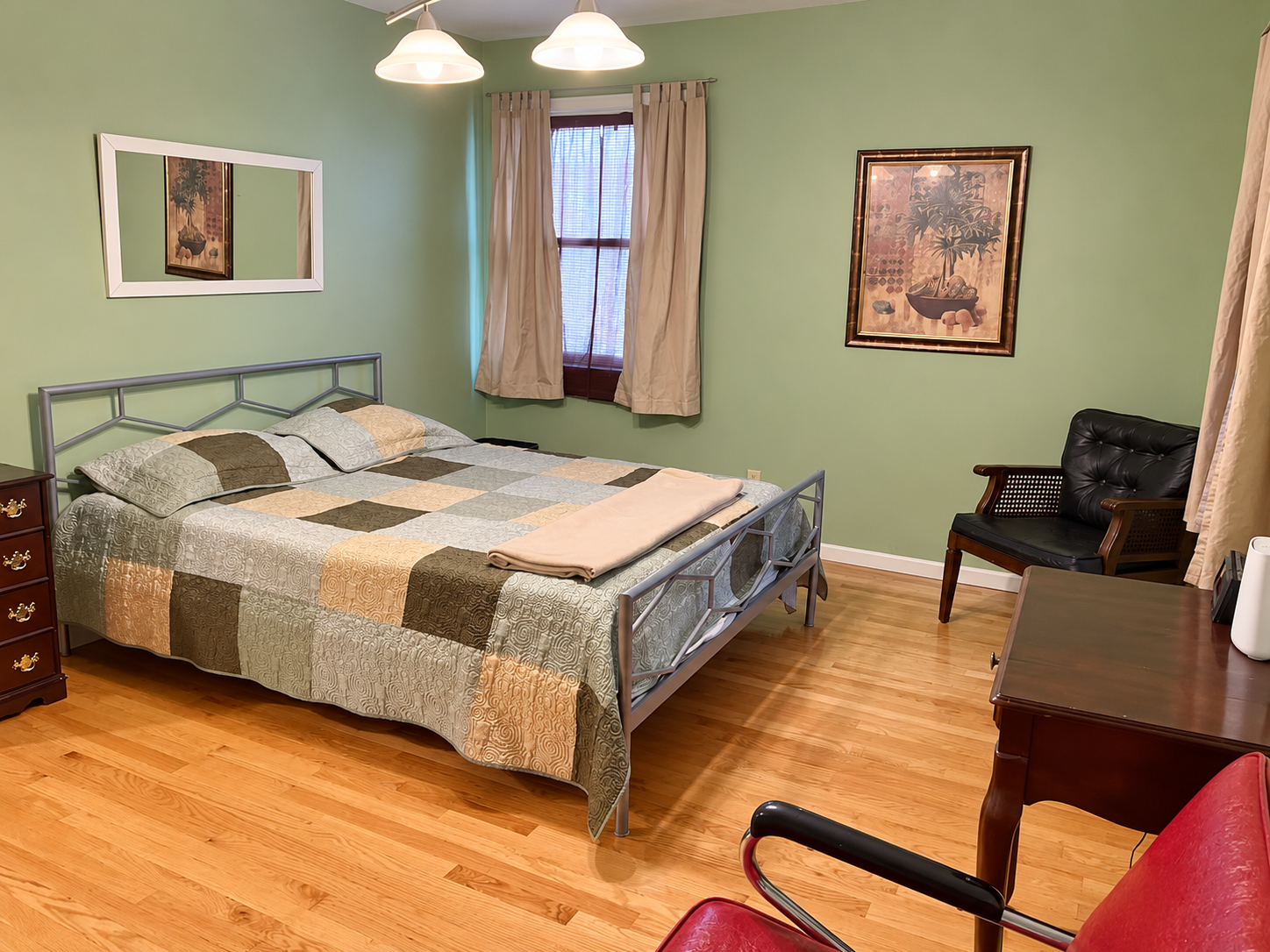 Spacious queen bedroom with hardwood floors and a writing desk