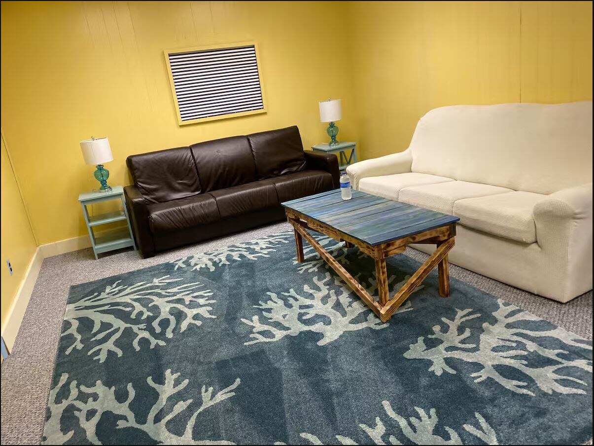 Bright coastal living room with sofas and a patterned blue rug