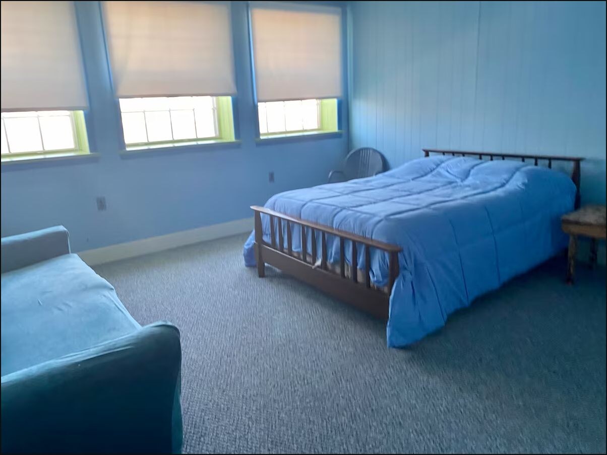 Blue bedroom with a queen bed and three windows