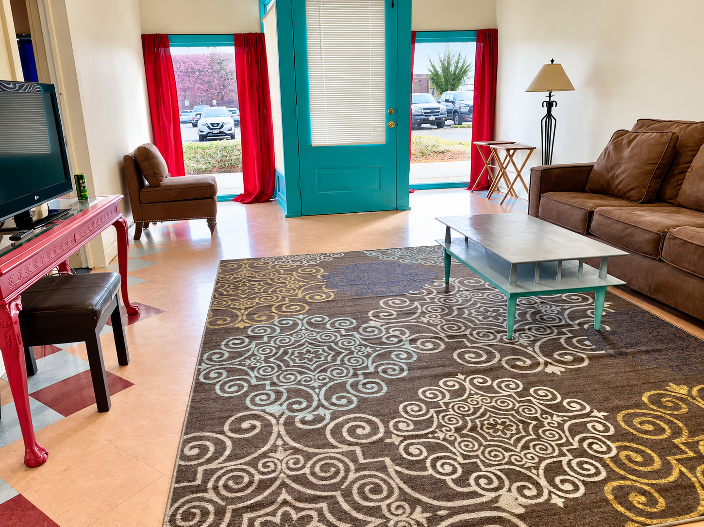 Bright living room with teal doors, red curtains, and patterned rug